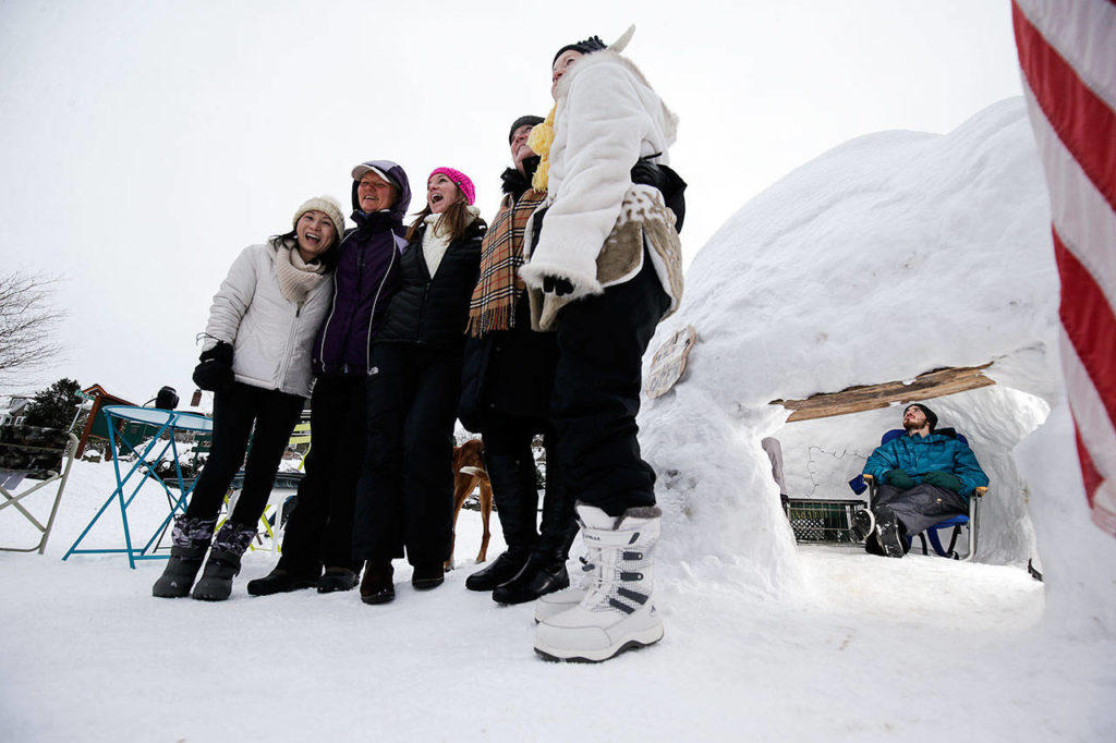 Neighbors gather for group photos Monday at Rucker Hill Park in Everett as Ethan Schmidt, 20, and a friend, Mitch Baker (not seen), sit inside “Cafe Igloo,” which was built by kids and parents. (Andy Bronson / The Herald)
