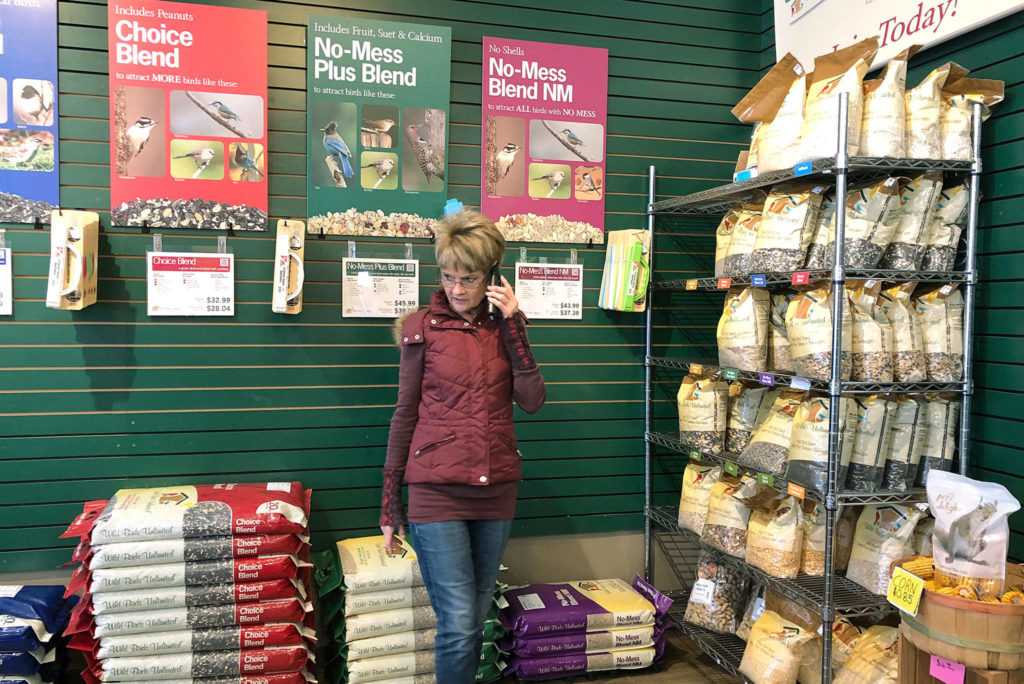 Kelly Haley at Wild Birds Unlimited in Everett advises a call-in customer. The bird seed bags are usually stacked high at the store, but supplies are running low. (Janice Podsada / The Herald)
