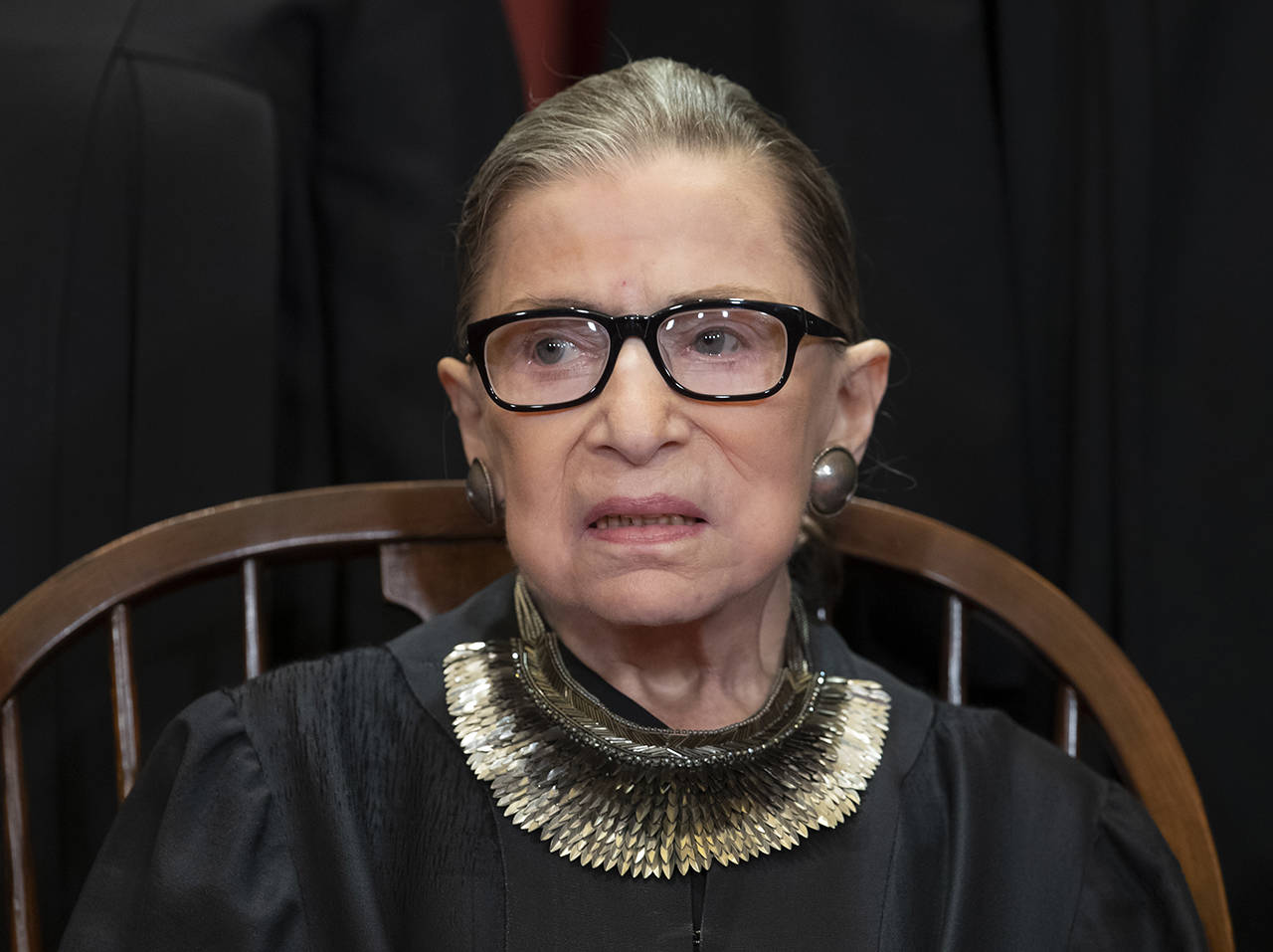 In this Nov. 30, 2018 photo, Associate Justice Ruth Bader Ginsburg sits with fellow Supreme Court justices for a group portrait at the Supreme Court Building in Washington. Ginsburg has missed a month of Supreme Court arguments as she recovers from lung cancer surgery. (AP Photo/J. Scott Applewhite, file)