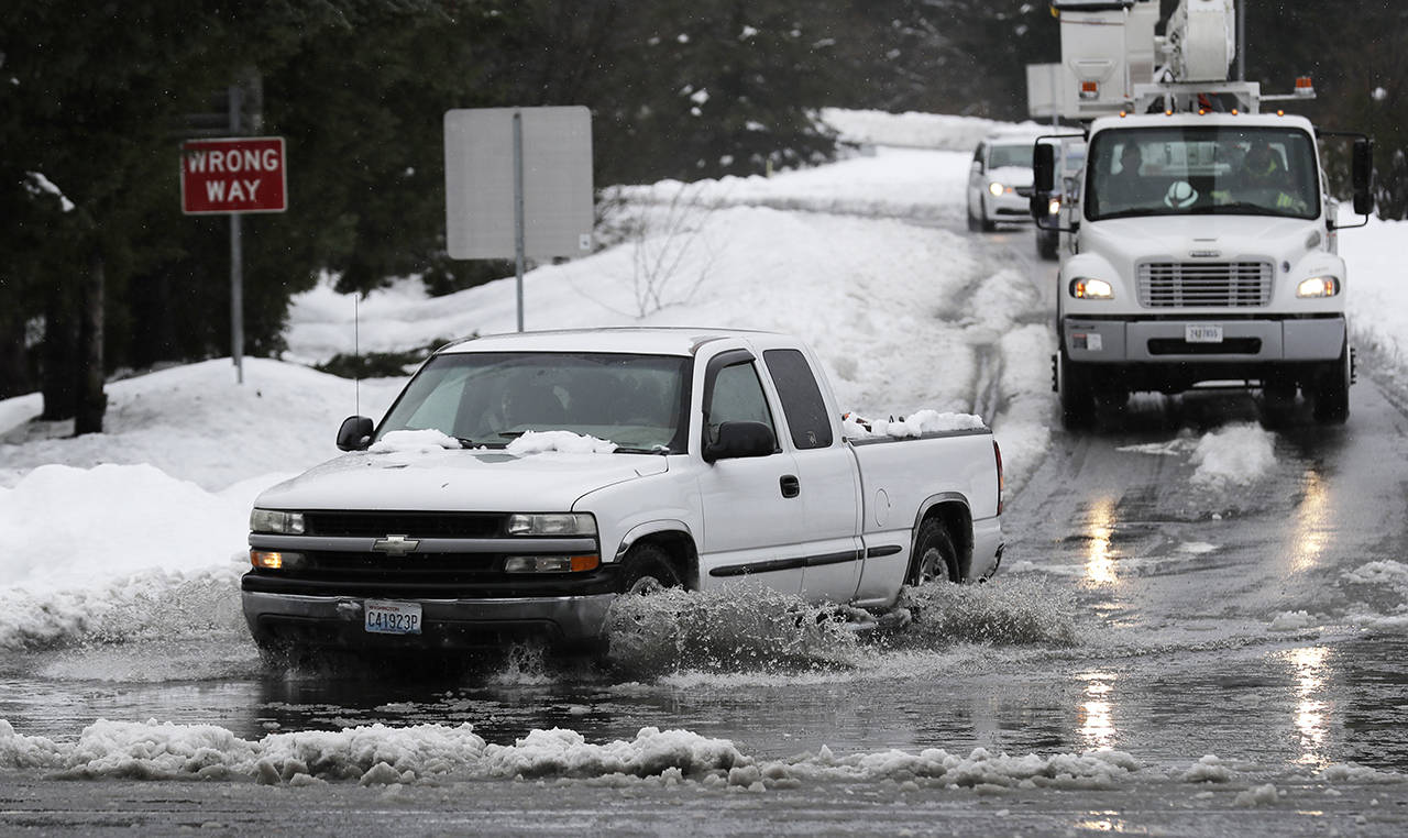 A truck drives through standing water on a highway offramp Tuesday in Olympia. (AP Photo/Ted S. Warren)