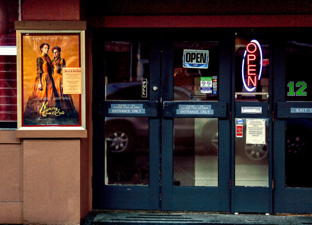 Edmonds Theater door glass reflects the bustling foot and auto traffic on Main Street. (Dan Bates / The Herald)
