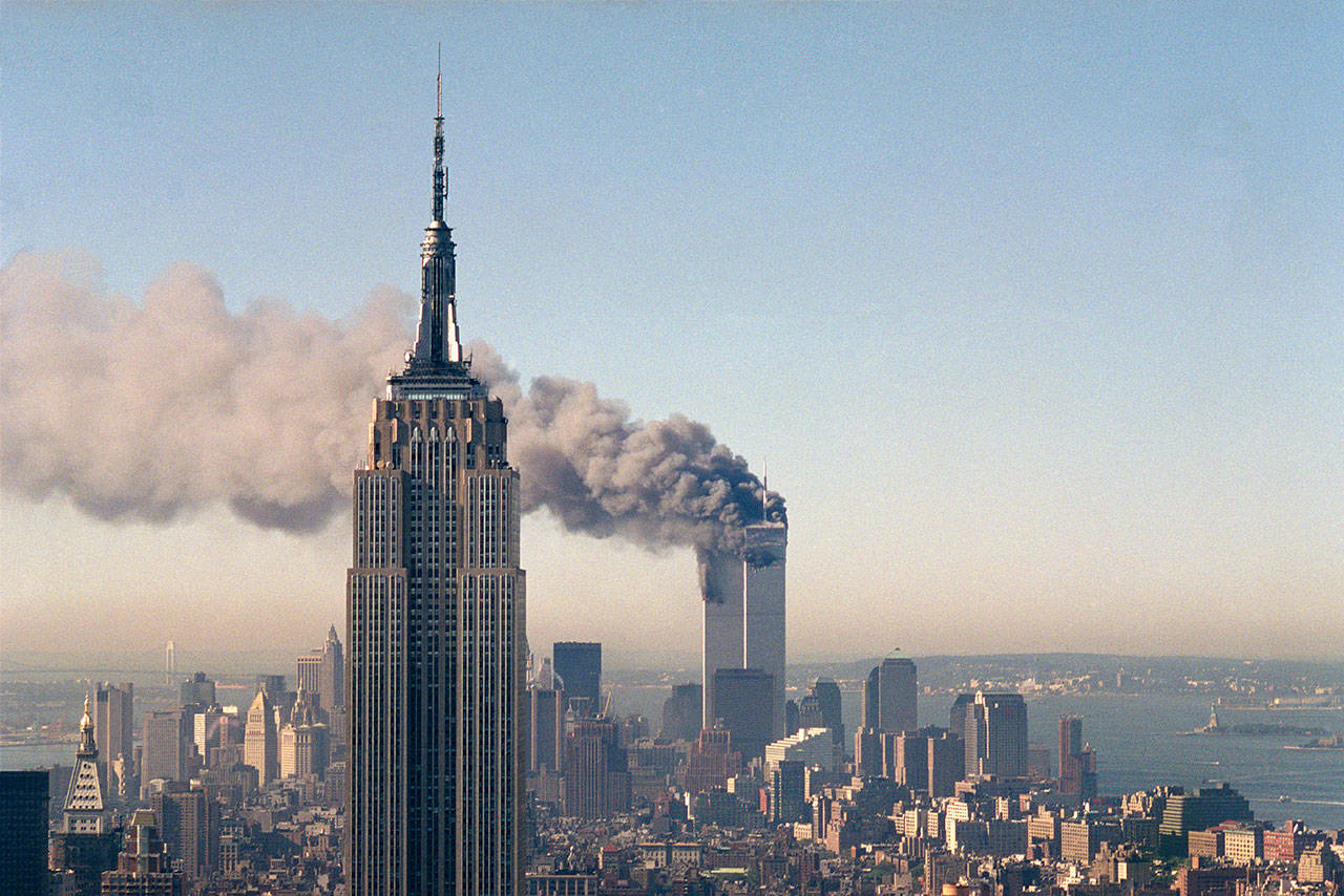 In this Sept. 11, 2001 photo, the twin towers of the World Trade Center burn behind the Empire State Building in New York. (AP Photo/Marty Lederhandler, File)