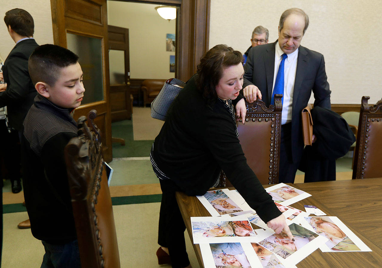 Freedom Nitschke (center) and her son Julian Martinez, 11 (left), look at photos Friday during a news conference in Olympia as Sen. Steve O’Ban, R-University Place (right) looks on. (AP Photo/Ted S. Warren)