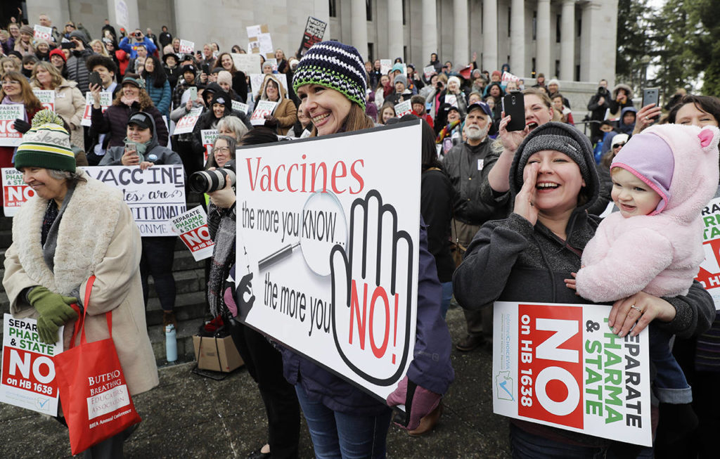 Lacey Walter, of Kennewick, holds a sign Feb 8 that reads “Vaccines, the more you know, the more you No!” (AP Photo/Ted S. Warren, file)
