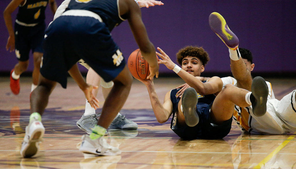 Mariner’s Henry Avra looks to throw a pass after scrambling on the court for a loose ball Monday, Feb. 18, in a district boys’ basketball game at North Creek High in Bothell. (Andy Bronson / The Herald)
