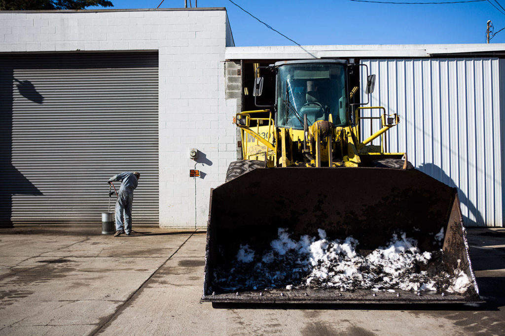 NW Washington Compost employees prep the plow they are lending to help plow snow-covered roads on Thursday in Darrington. (Olivia Vanni / The Herald)
