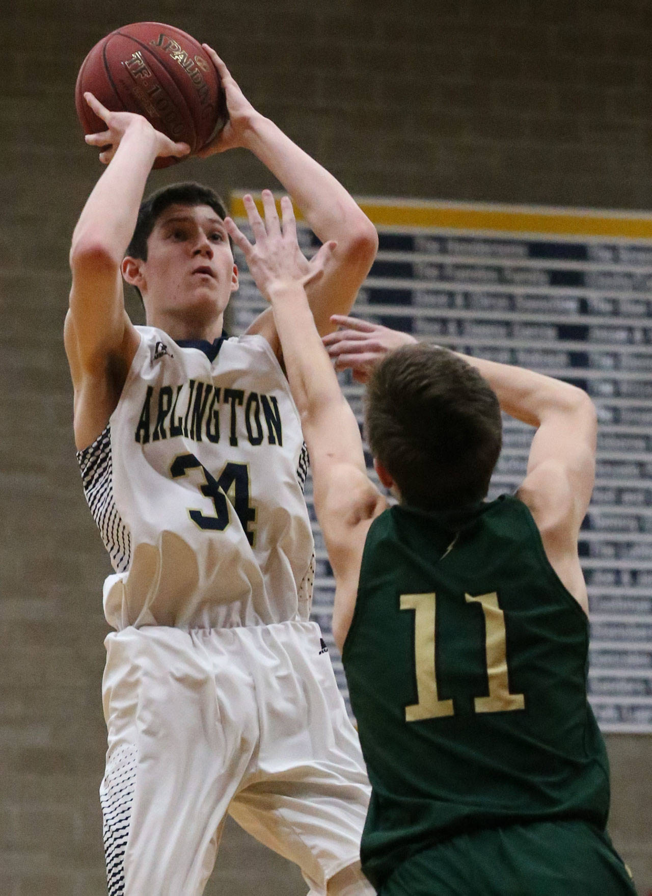 Arlington’s Josh Gutierrez attempts a 3-pointer over the outstretched arm of Marysville Getchell’s Cole Norton during a 3A District 1 Tournament game on Feb. 15 in Arlington. Gutierrez and the Eagles will face Wilson in a 3A state regional game Friday. (Kevin Clark / The Herald)
