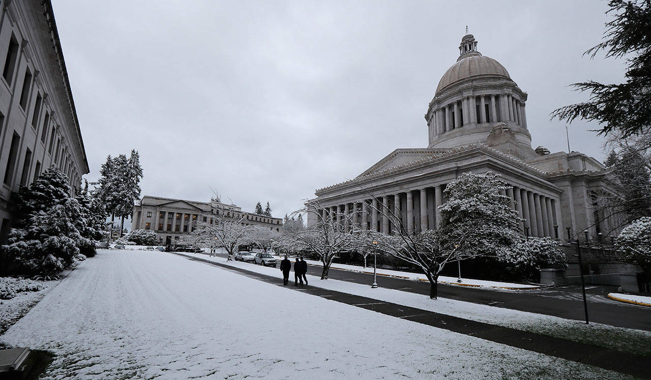 Pedestrians walk past the Legislative Building at the Capitol in Olympia, on Feb. 4, following an overnight snowfall. (Ted S. Warren/Associated Press)