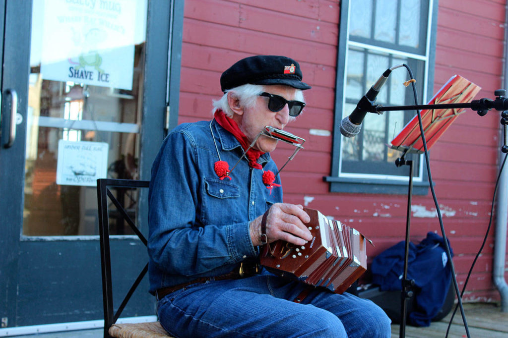 Peter Lawlor plays sea shanties on his concertina and harmonica on the Coupeville wharf during a birthday party for a historic schooner. (Patricia Guthrie/South Whidbey Record file)
