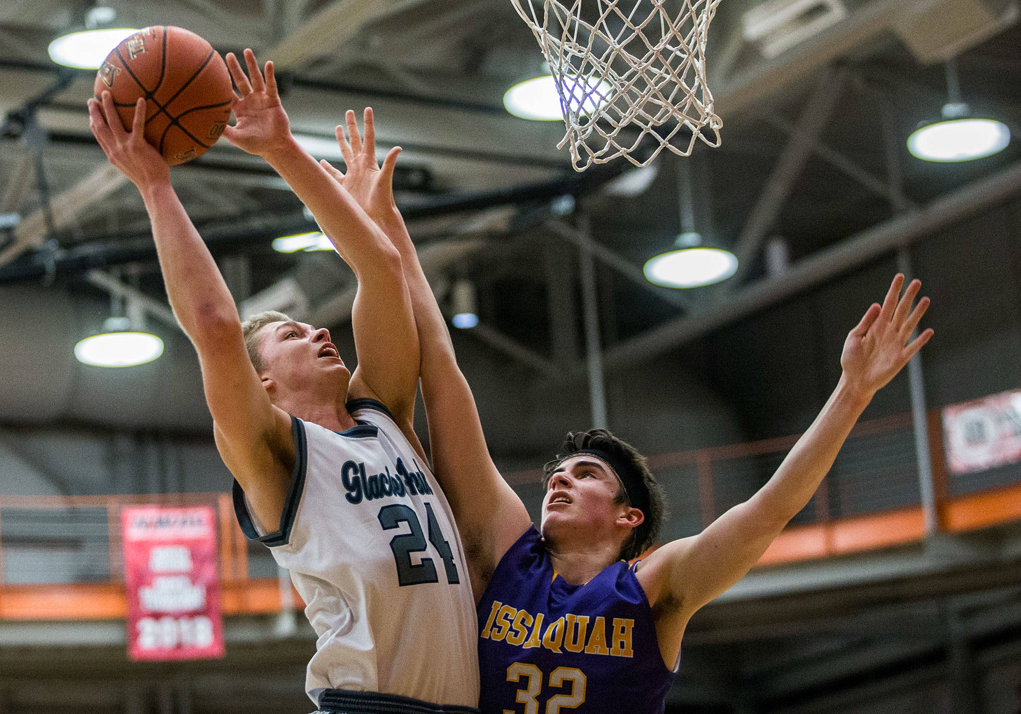 Glacier Peak’s Evan Mannes (left) attempts a layup over Issaquah’s Charlie Dietiker during Friday’s 4A state regional game at Everett Community College. (Olivia Vanni / The Herald)