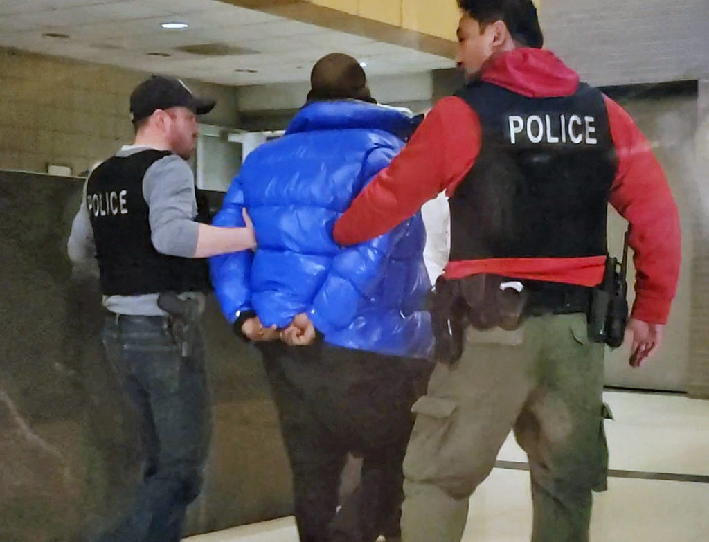 In this still image taken from video, R. Kelly is escorted by police in custody at the Chicago Police Department’s Central District Friday night in Chicago. (Nader Issa/Chicago Sun-Times via AP)
