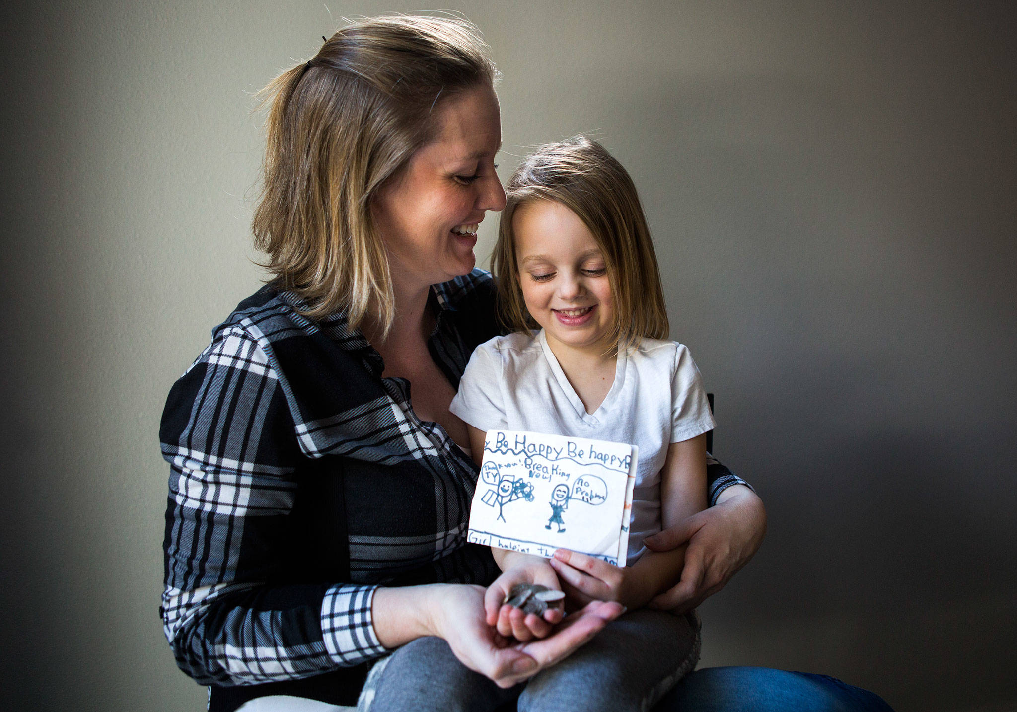 Jessica Beckstrand, left, sits with her daughter Layla, 4, holding some of the money raised and cards made for their family’s non-profit, Strong Cares Guild, at their home on Tuesday, Feb. 26, 2019 in Marysville, Wash. (Olivia Vanni / The Herald)
