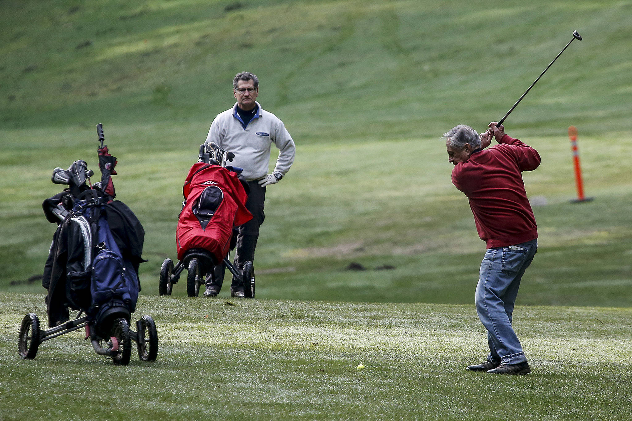 Ray Weis (right) takes a swing while golfing with friend Jim Fenton at the Kayak Point Golf Course in 2018. (Ian Terry / Herald file)