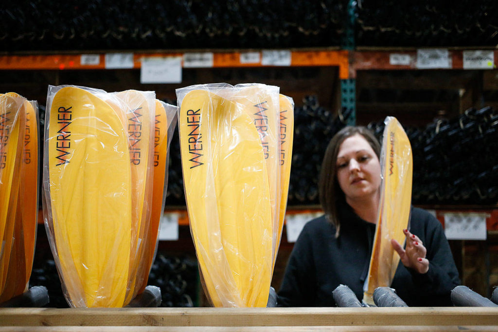 Werner Paddles shipper Crystal Habowski stacks kayak paddles before boxing them up at the company’s plant in Monroe. (Andy Bronson / The Herald)
