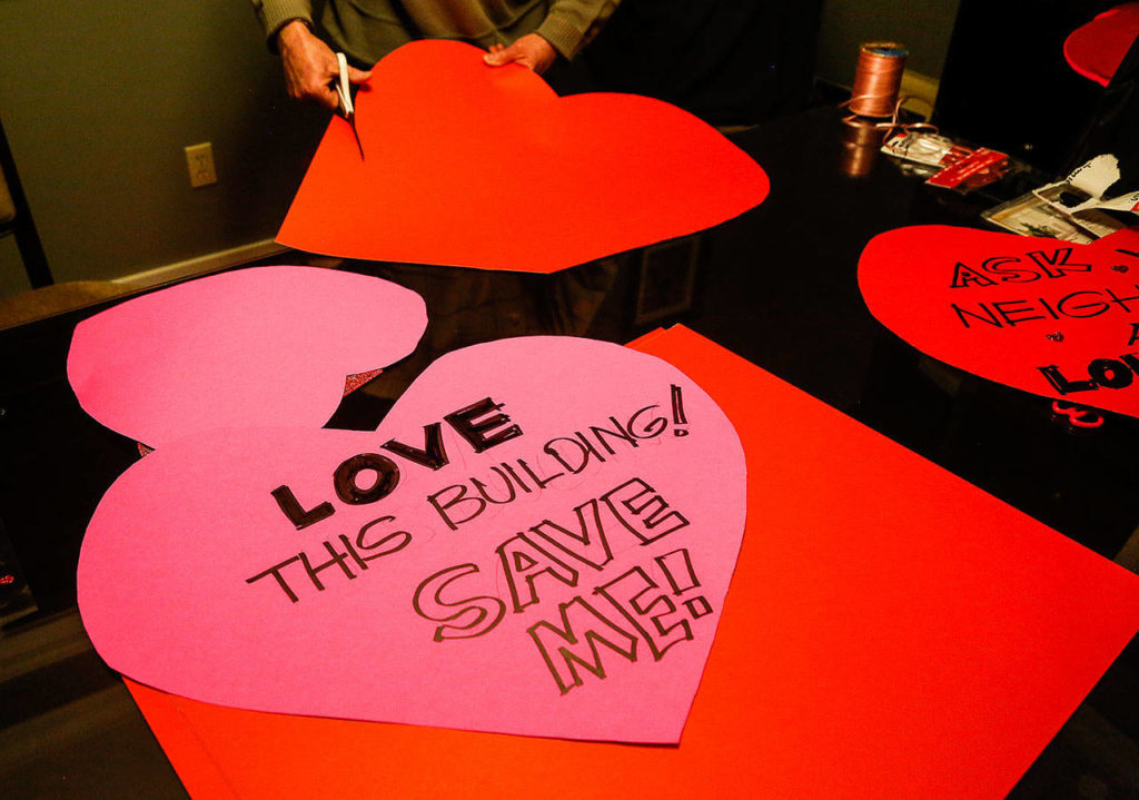 Patrick Hall cuts out large cardboard hearts Thursday evening for Friday’s “heart-bombing” at Everett’s 108-year-old Longfellow School building. (Dan Bates / The Herald)
