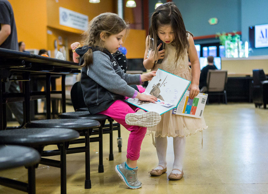 Maci Knapstad, 5 (left), reads her Dr. Seuss book to Phoebe Baker, 5, during the Assistance League of Everett’s book donation event at the Granite Falls Boys & Girls Club on Feb. 28 in Granite Falls. (Olivia Vanni / The Herald)
