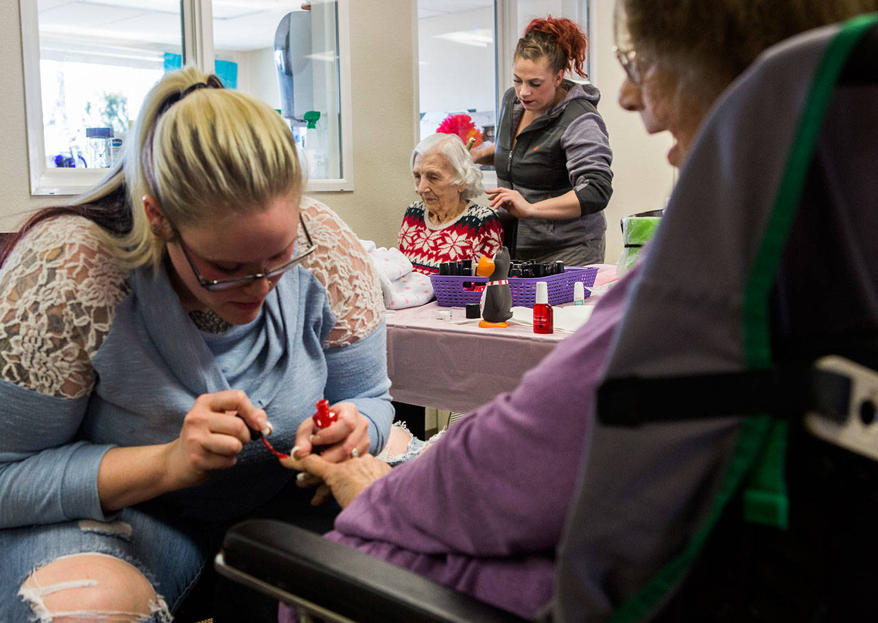 A resident, center, gets her hair done while others get their nails done during a beauty day at the Josephine Caring Community on Saturday, March 9, 2019 in Stanwood, Wash. (Olivia Vanni / The Herald)