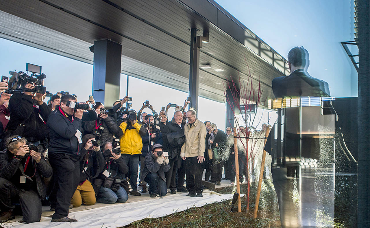 Brett Smith smashes a bottle of champagne against the new building as press take photos during the grand-opening of the Paine Field airport on Monday in Everett. (Olivia Vanni / The Herald)