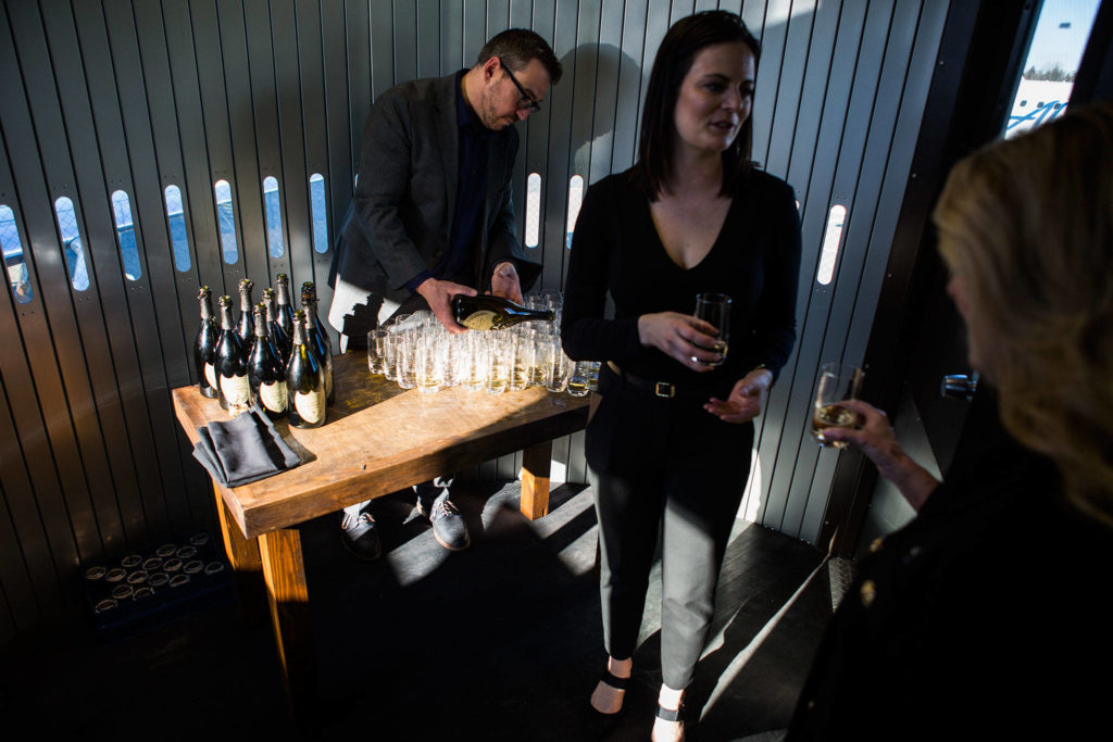 VIPs boarding the first flight are handed glasses of Dom Perignon for an on-board toast during the grand opening of the Paine Field Airport on March 4 in Everett. (Olivia Vanni / The Herald)
