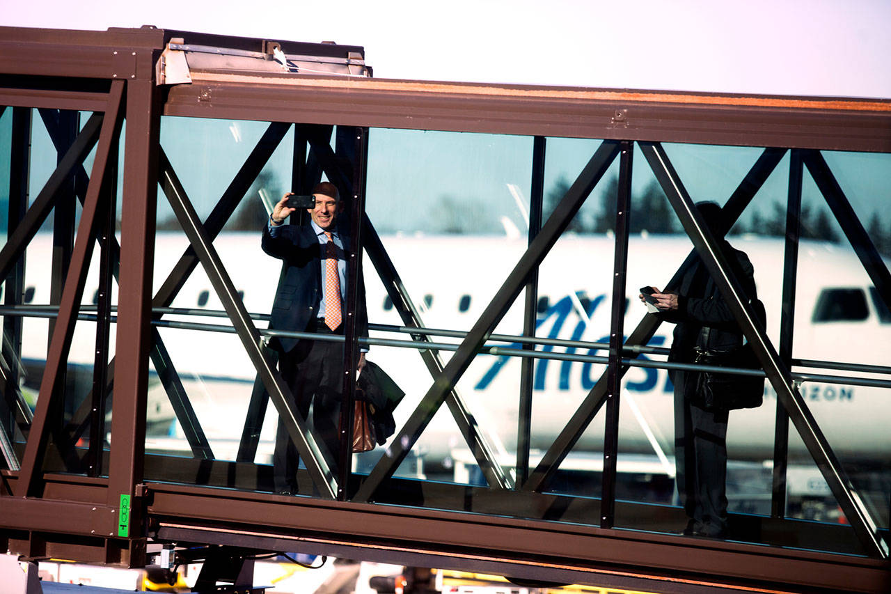 A passenger takes a photo from the glass gangway while boarding an Alaska Airlines flight on first day of regular airline service at Paine Field terminal on Monday in Everett. (Andy Bronson / The Herald)