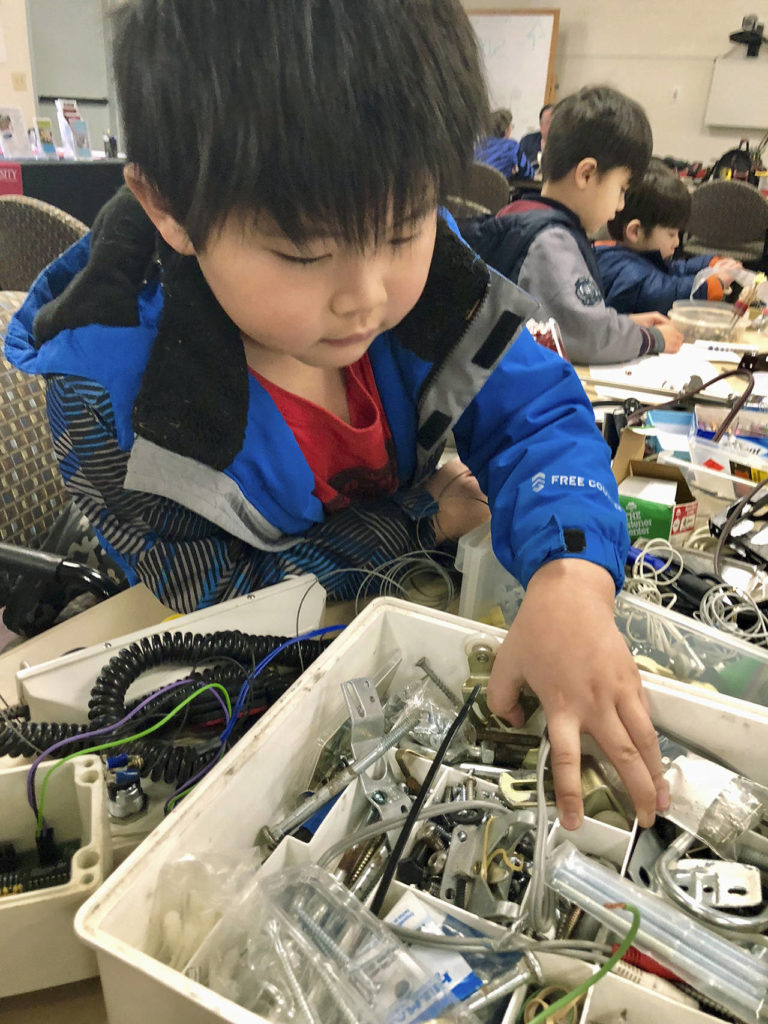 While his bike gets fixed, Jesse Wong, 6, of Edmonds, digs through the bins at the Repair Cafe creation station where kids can make things to take home. (Andrea Brown / The Herald)
