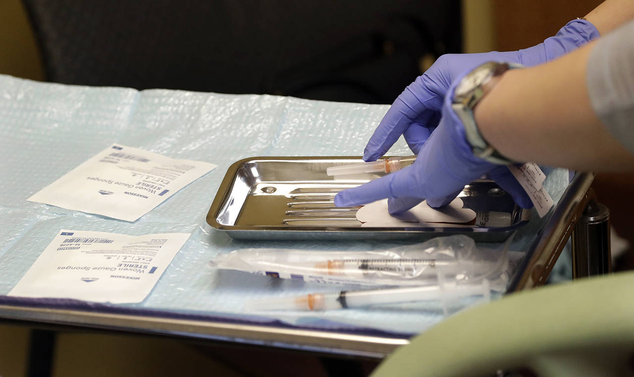 In this Feb. 13 photo, a health care worker prepares syringes, including a vaccine for measles, mumps, and rubella (MMR), for a child’s inoculations at the International Community Health Services in Seattle. (AP Photo/Elaine Thompson, File)