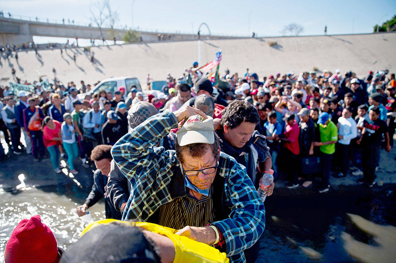 Migrants cross the river at the Mexico-U.S. border after pushing past a line of Mexican police at the Chaparral crossing in Tijuana, Mexico, on Nov. 25, 2018. (AP Photo/Ramon Espinosa, File)