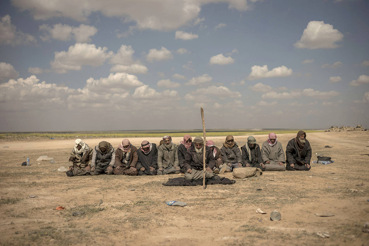 In this March 6 photo, men pray at a reception area for people evacuated from the last shred of territory held by Islamic State militants, outside Baghouz, Syria. (AP Photo/Gabriel Chaim)
