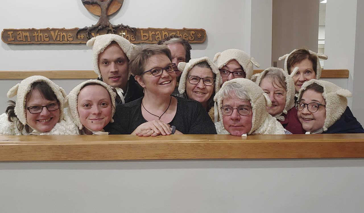 Director Jennifer Rodgers (center) is surrounded by members of the Everett Chorale dressed in one of the costumes they will wear at their March 30 concert. (Chase Dermott)