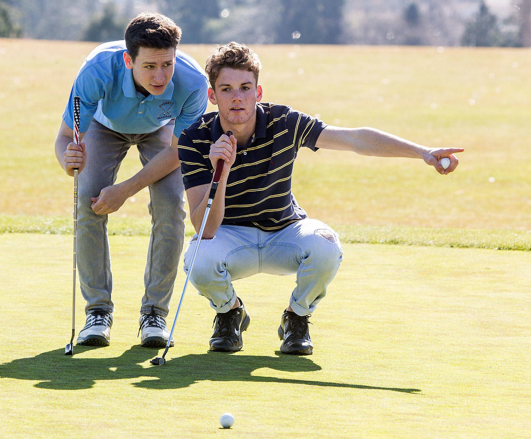 Everett’s Andrew Olson (left) and Ronny Kildall discuss the slope of the green as they line up their putts during a team practice Monday at Legion Memorial Golf Course in Everett. (Andy Bronson / The Herald)