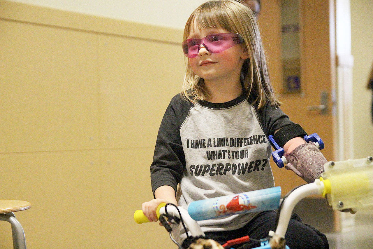 Michaela Reed navigates an obstacle course of stools in the hallway of Oak Harbor High School with her new bike. (Laura Guido / Whidbey News-Times)