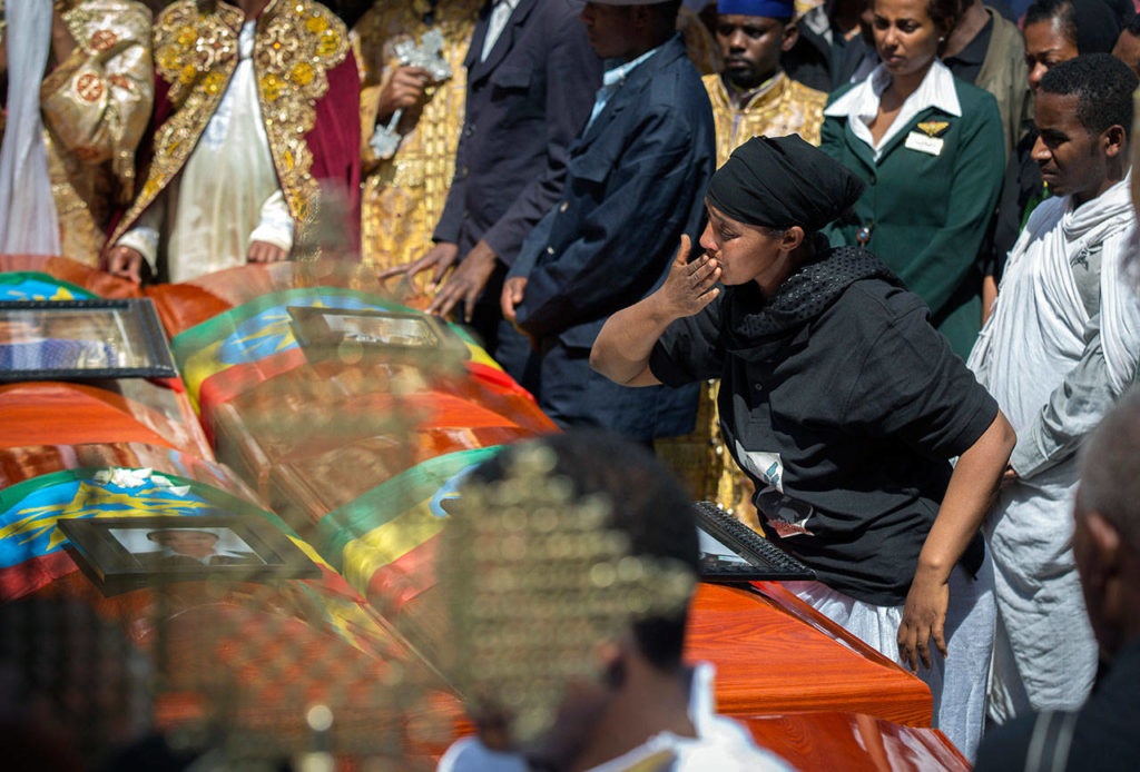 A relative blows a kiss toward empty caskets draped with the national flag at a mass funeral Sunday in Addis Ababa, Ethiopia. Thousands of Ethiopians turned out one week after an Ethiopian Airlines plane crash. (AP Photo/Mulugeta Ayene) 
