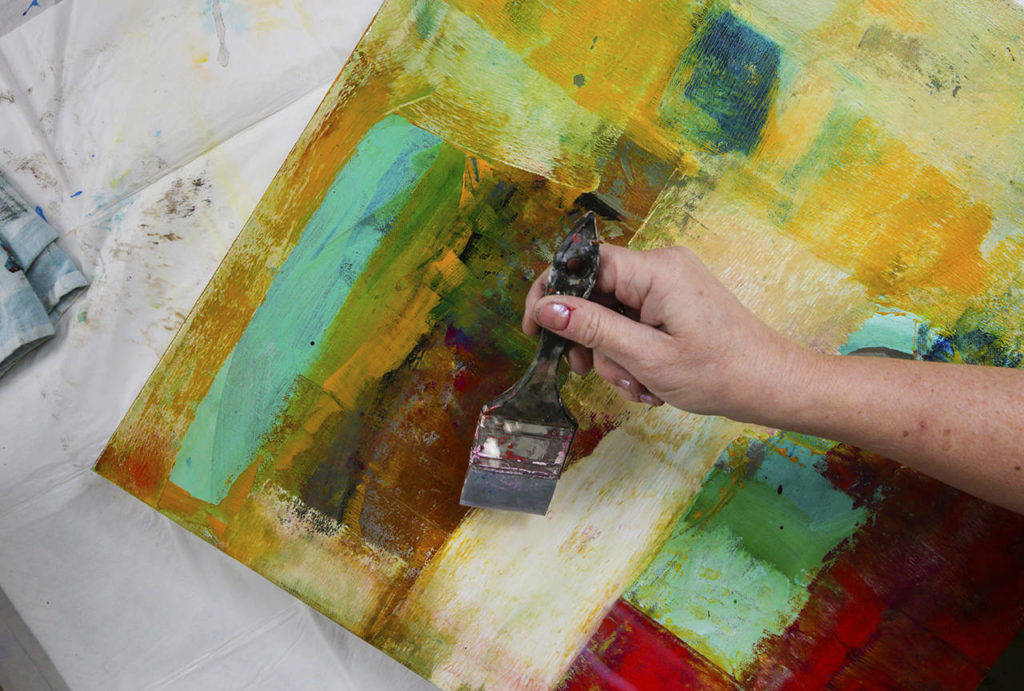 Cort puts a coat of varnish on a painting. (Andy Bronson / The Herald)
