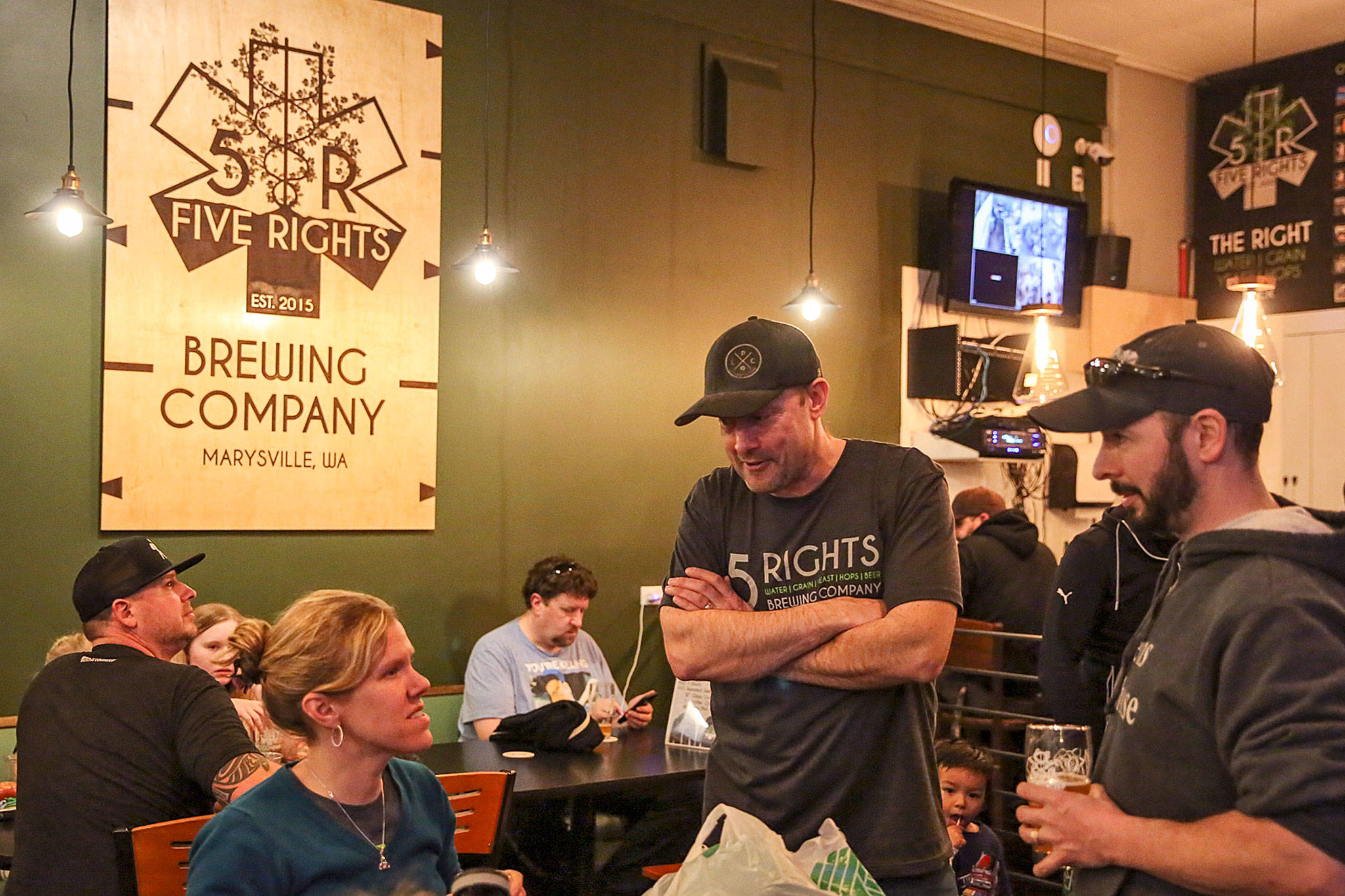 R.J. Whitlow (center) talks with customers during the soft opening of 5 Rights Brewing Taproom in Marysville on March 15. (Kevin Clark / The Herald)