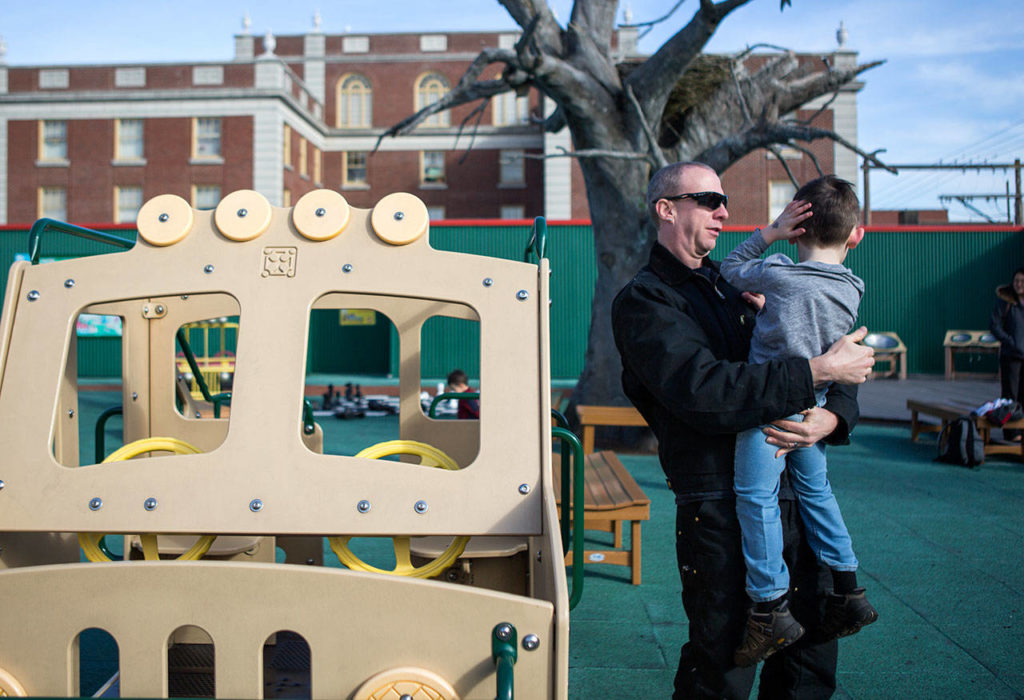Robert Torres-Miller holds his grandson Kevin after he bumped his head on the play structure at the Imagine Children’s Museum. (Olivia Vanni / The Herald)
