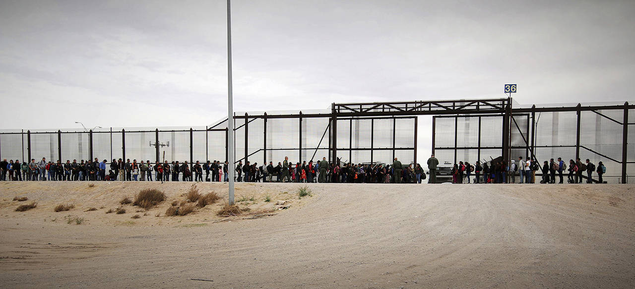 Migrants are shown lined up outside the wall in El Paso, Texas, on March 7. This group of 127 Guatemalan migrants had waded through the river to turn themselves in to U.S. agents, the first step in initiating the asylum process. (U.S. Customs and Border Protection)