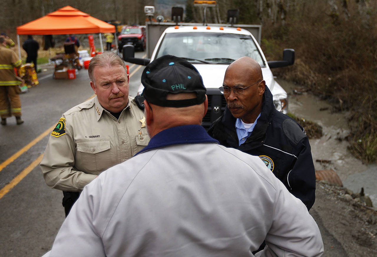 Snohomish County Sheriff Ty Trenary and County Executive John Lovick talk with volunteers and workers at the western edge of the mudslide where it covers Highway 530 on March 26, 2014. (Mark Mulligan / The Herald)