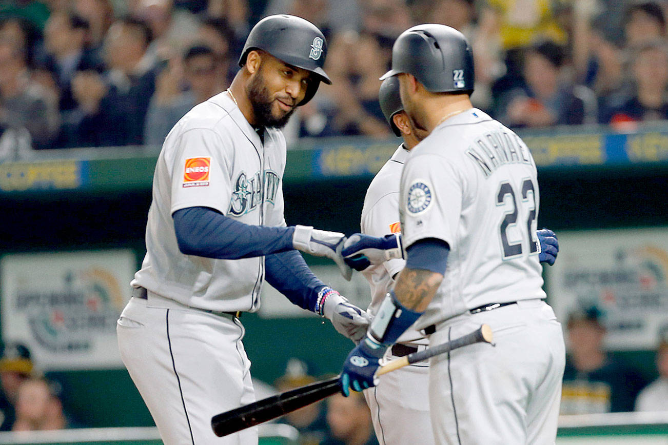 Seattle Mariners’ Domingo Santana, center, celebrates with teammate catcher Omar Narvaez (22) at home after hitting a grand slam off Oakland Athletics starter Mike Fiers in the third inning of Game 1 of their Major League opening series baseball game at Tokyo Dome in Tokyo, Wednesday, March 20, 2019. Left is Athletics catcher Nick Hundley. (AP Photo/Toru Takahashi)