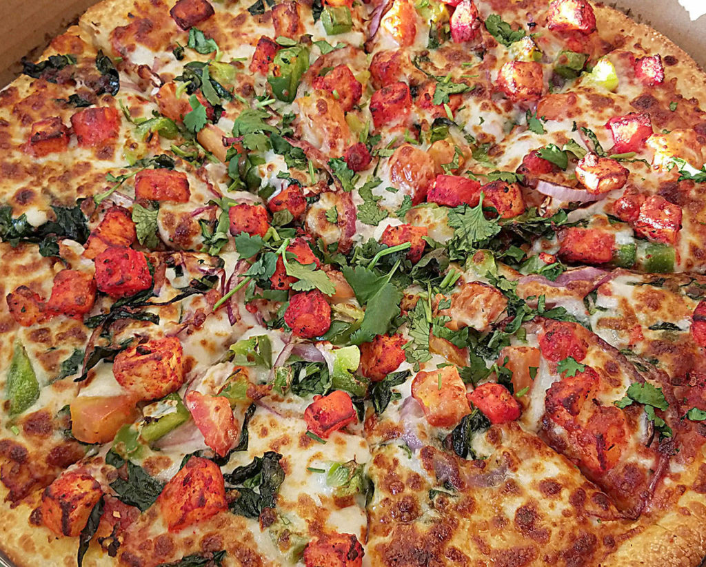The palak paneer pizza at Can Am has a mix of red onions, green peppers, tomatoes, spinach and paneer marinated in the store’s sauce and mozzarella cheese. (Sharon Salyer/The Herald)
