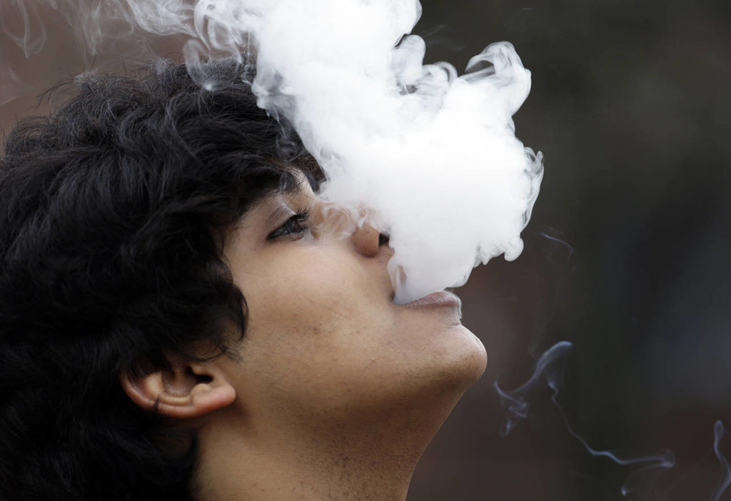 In this 2016 photo, a man who declined to be identified blows out a cloud of smoke as he puffs on a small pipe outside at Seattle Central College in Seattle. A proposal to raise Washington’s smoking and vaping age to 21 passed the Legislature on Wednesday, putting the state on the precipice of becoming the ninth state to make such a change. (AP Photo/Elaine Thompson, File)
