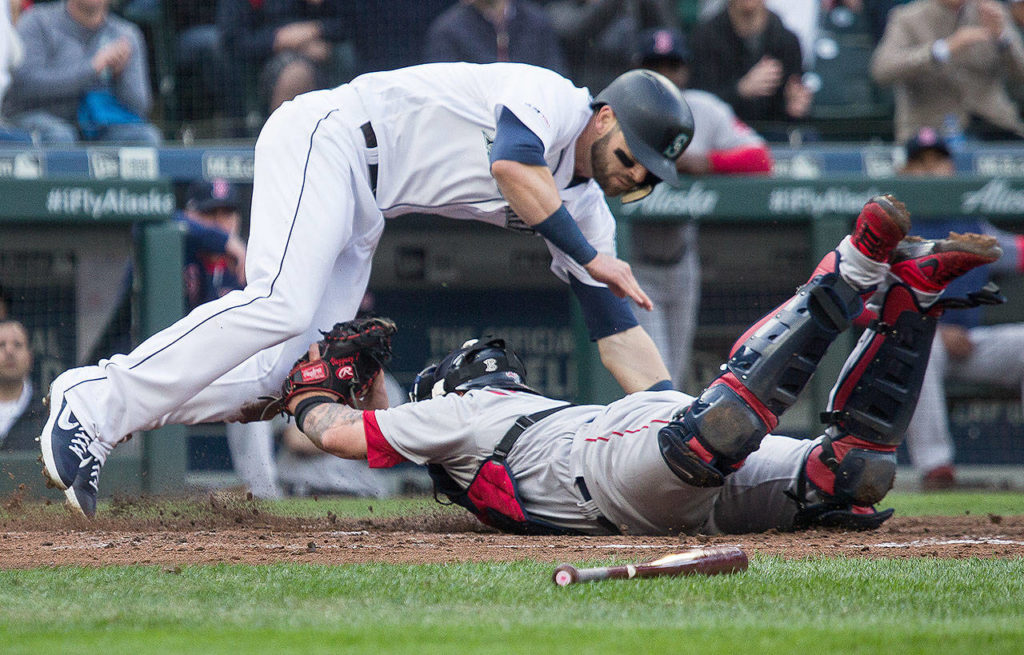 The Mariners’ Mitch Haniger (left) tries to avoid the tag by Red Sox catcher Christian Vazquez during a game on March 28, 2019, at T-Mobile Park in Seattle. (Andy Bronson / The Herald)
