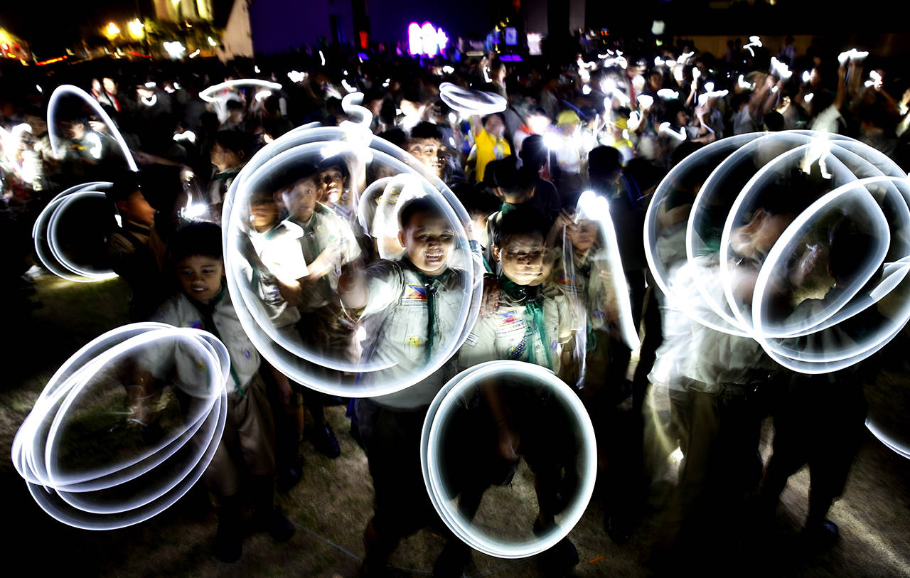 Philippine Boy Scouts play with their flashlights at the countdown for the 12th Earth Hour event Saturday in suburban Makati city east of Manila, Philippines. Earth Hour is the symbolic switching off of the lights for one hour to help minimize fossil fuel consumption as well as mitigate the effects of climate change. (AP Photo/Bullit Marquez)
