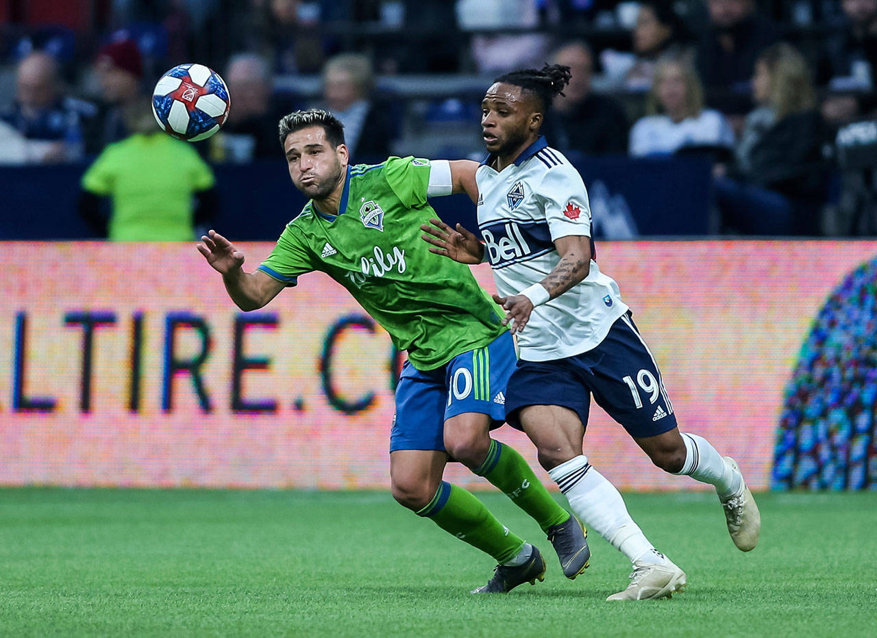 The Whitecaps’ Lass Bangoura (19) kicks the ball near the Sounders’ Nicolas Loderio (10) during the first half of an MLS match on March 30, 2019, in Vancouver, British Columbia. (Ben Nelms/The Canadian Press via AP)