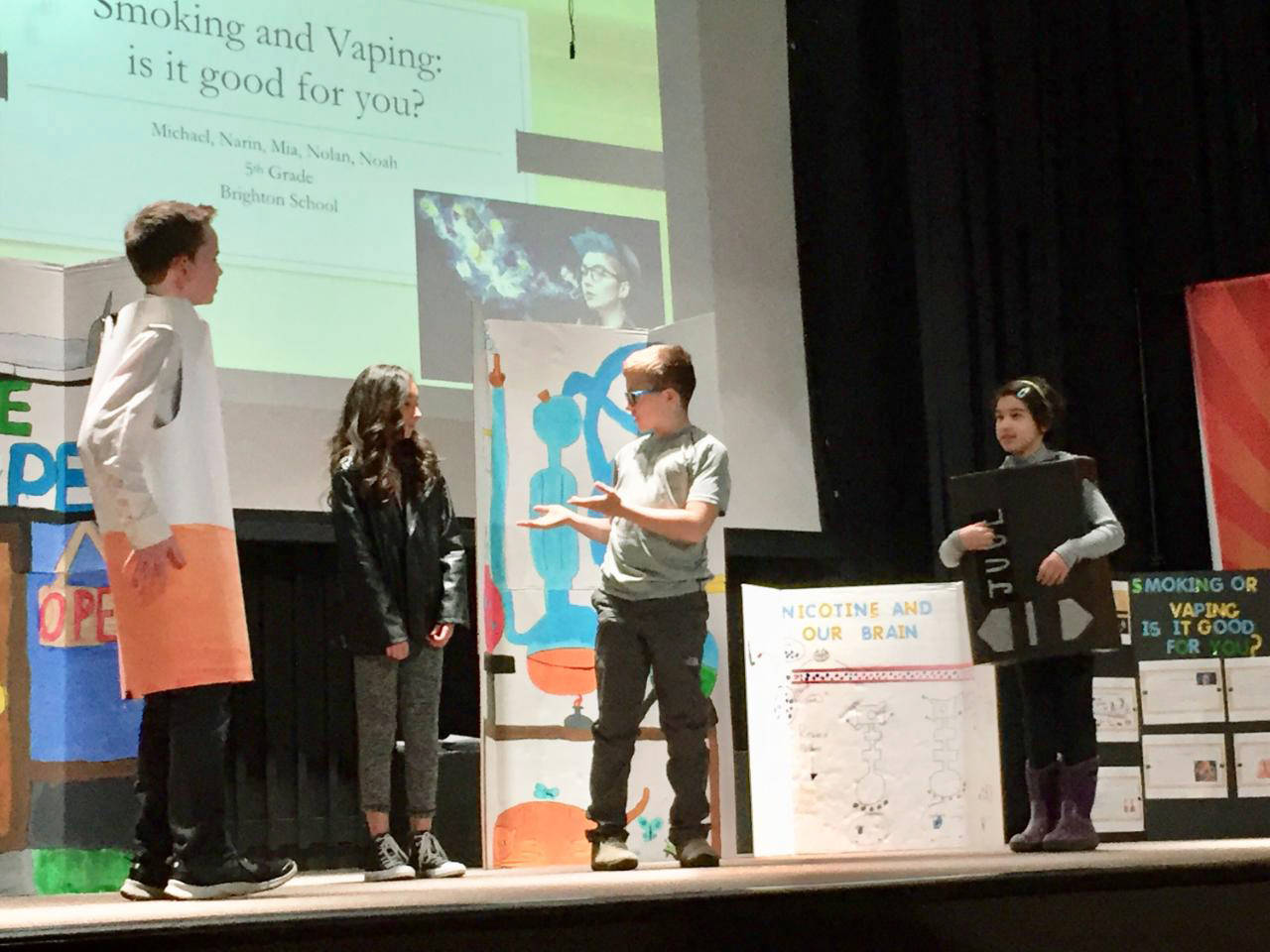 Nolan Walsh, playing the character “Cigarette,” Michael Usoltsev in the role of scientist, and Narinayse Vural, playing her character, a vaping device. (Brighton School)