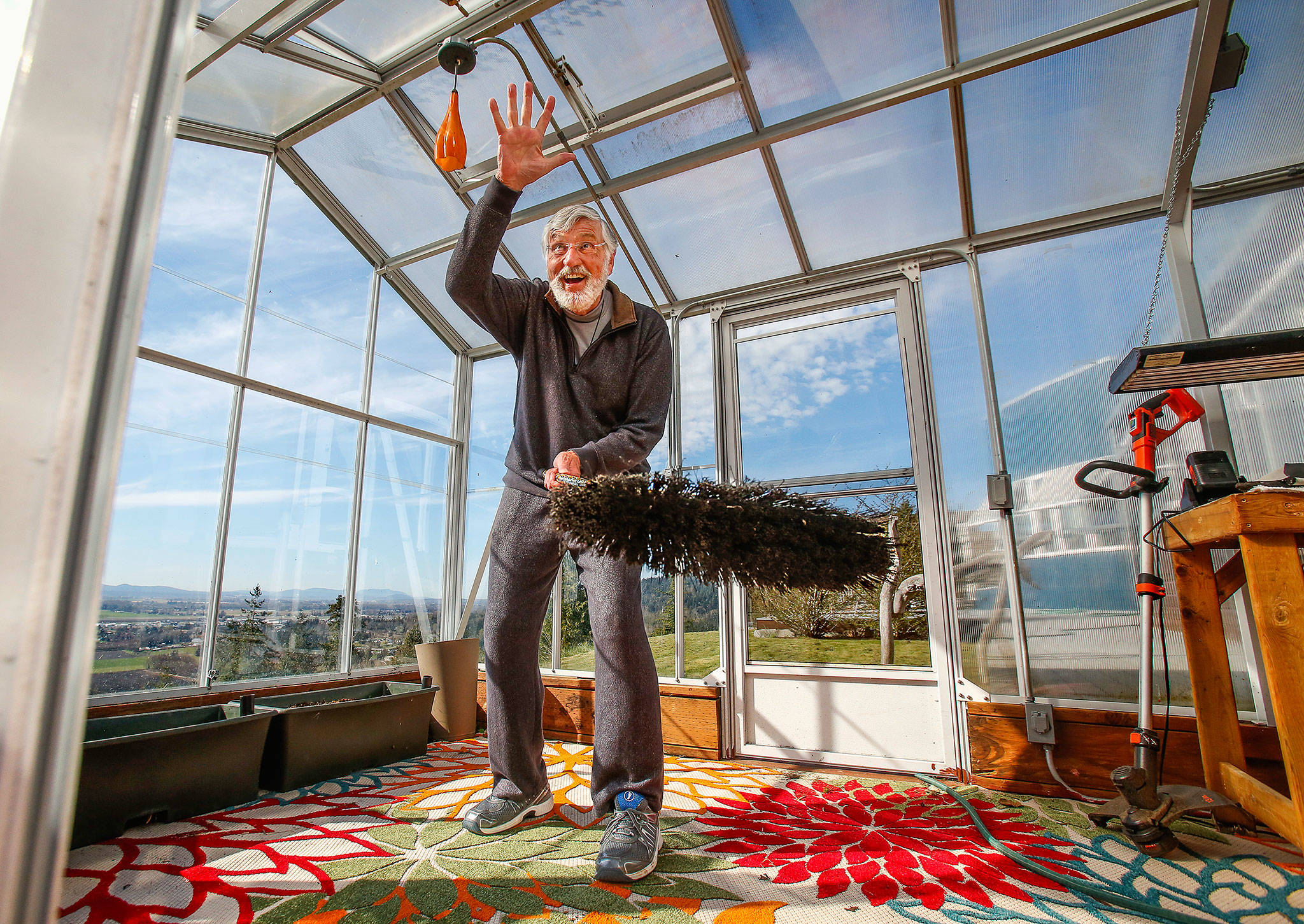 Holding a broom, Graham Kerr explains Monday how he saved a bird that had become trapped in his greenhouse. He plans to tell the story at the YMCA prayer breakfast April 19. (Dan Bates / The Herald)