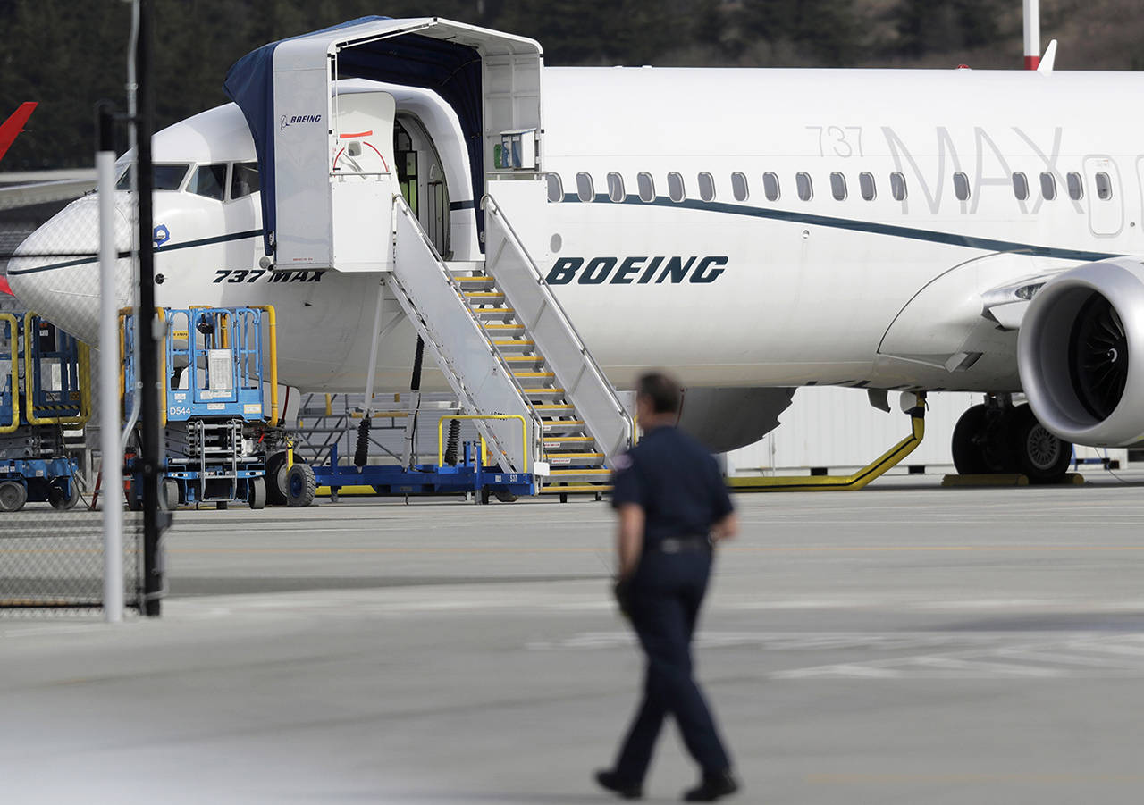 In this March 14 photo, a worker walks next to a Boeing 737 MAX 8 airplane parked at Boeing Field in Seattle. (AP Photo/Ted S. Warren, File)