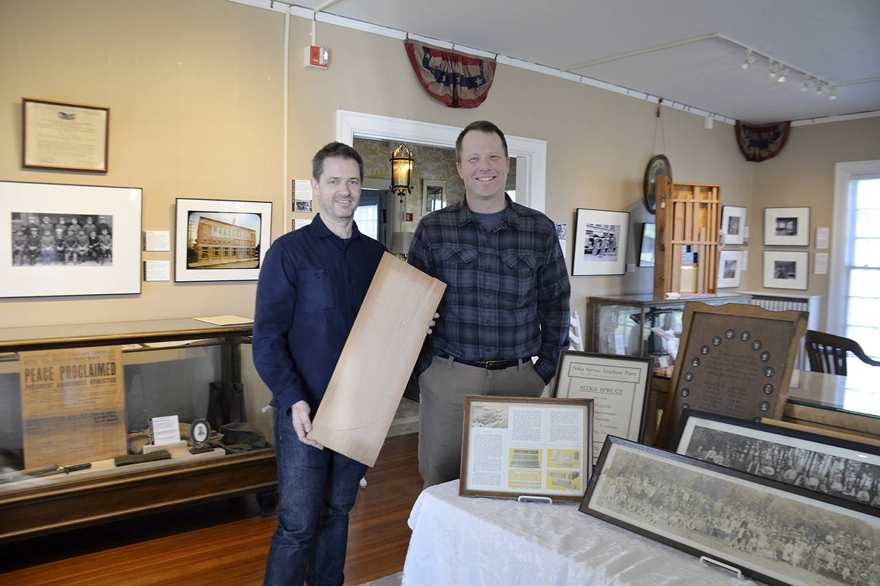 Australian Professor Chris Gibson (left) stands with Polson Museum Director John Larson. Gibson is holding a piece of wood from the Posey Manufacturing Company. (Louis Krauss / Grays Harbor News Group)