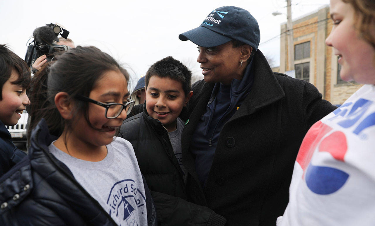 Grammar school students stop to say hello and hug mayoral candidate Lori Lightfoot outside a 14th Ward polling location Tuesday in Chicago. (Abel Uribe/Chicago Tribune via AP)