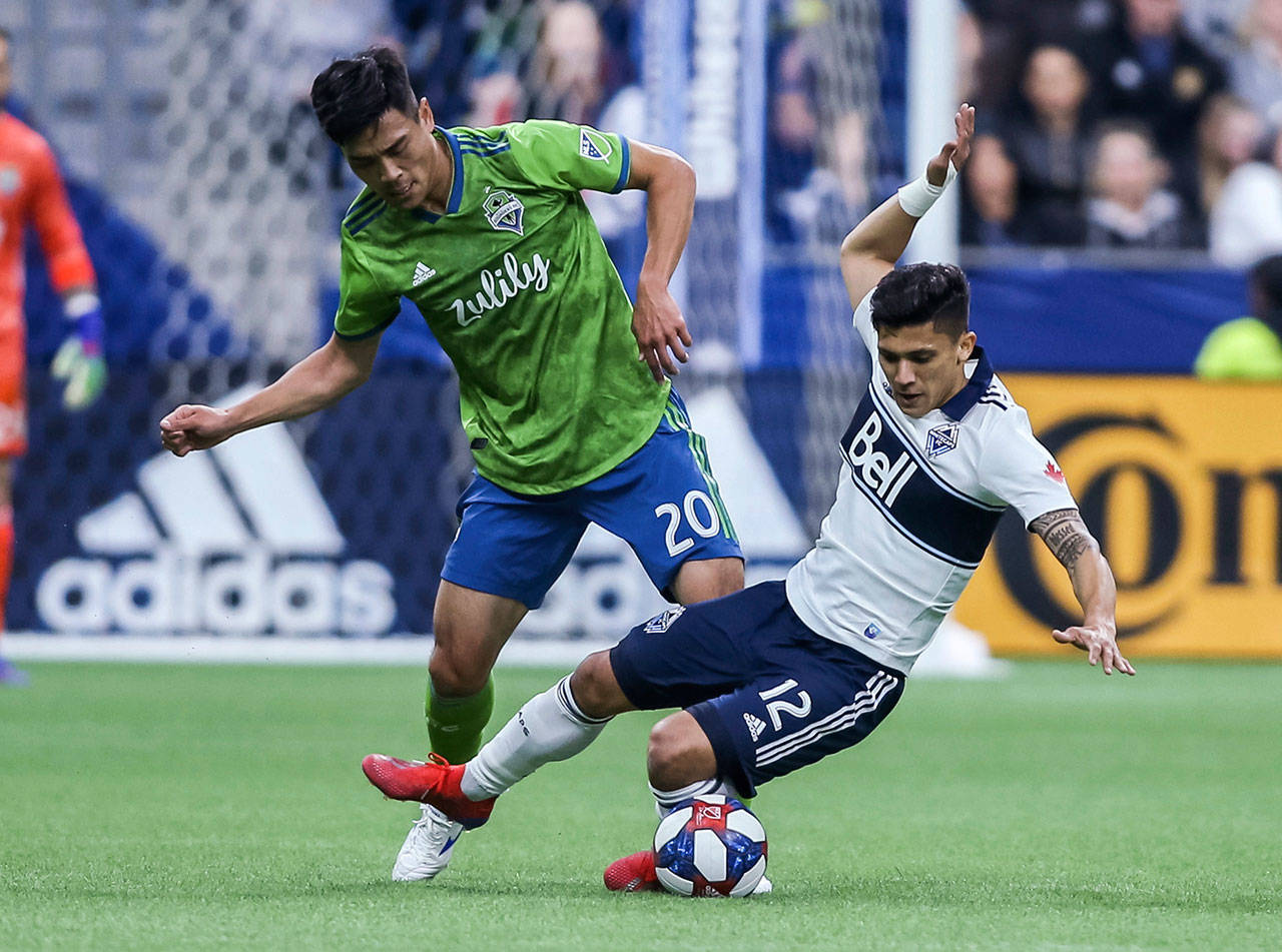 The Sounders’ Kim Kee-hee (20) tackles the Whitecaps’ Fredy Montero during the first half of an MLS match on March 30, 2019, in Vancouver, British Columbia. (Ben Nelms / The Canadian Press via AP)