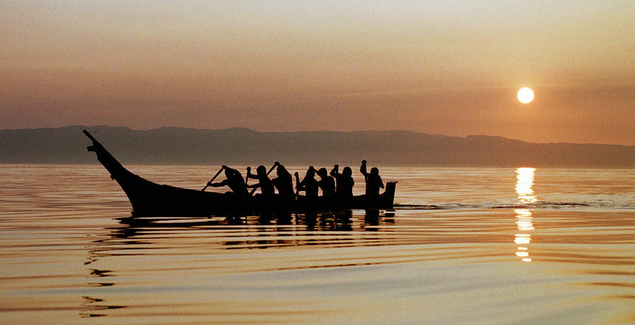 In this 1998 photo, Makah Indians paddle away from the rising sun as they head from Neah Bay toward open Pacific Ocean waters during a practice paddle ahead of its first whale hunt in 70 years. Federal officials are now supporting the Native American tribe’s decades-long request to resume whale hunts off the coast of Washington state. (AP Photo/Elaine Thompson, File)